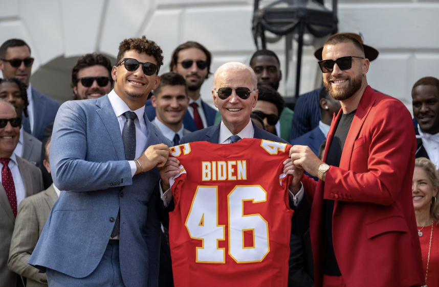 Kansas City Chiefs players Patrick Mahomes and Travis Kelce pose with Former President Joe Biden to commemorate their Super Bowl LVII win. 
